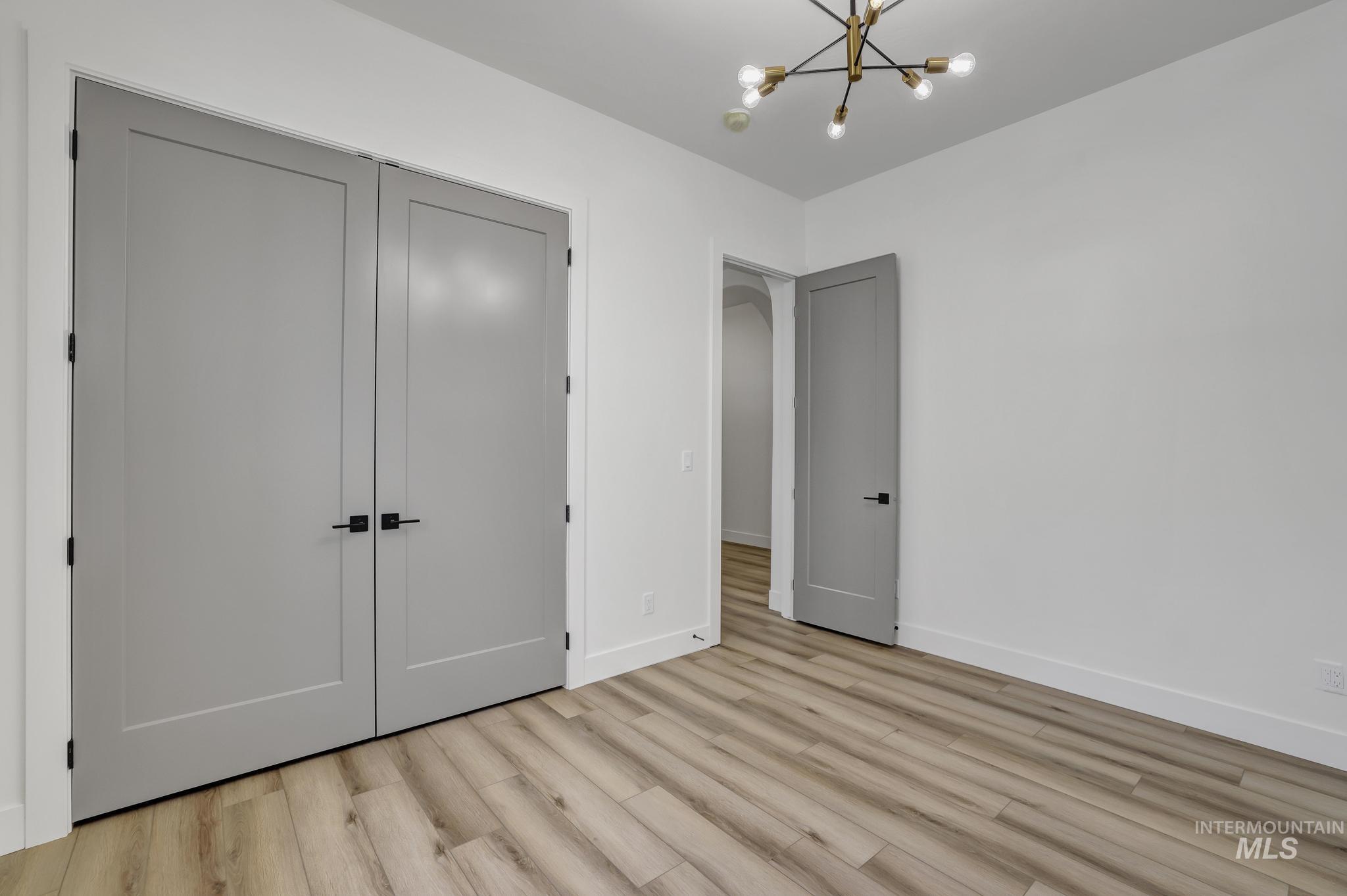 521 Falling Leaf Lane Twin Falls, ID 83301 - Photo 20 of 42 Unfurnished bedroom featuring a closet, light wood-style flooring, and a chandelier