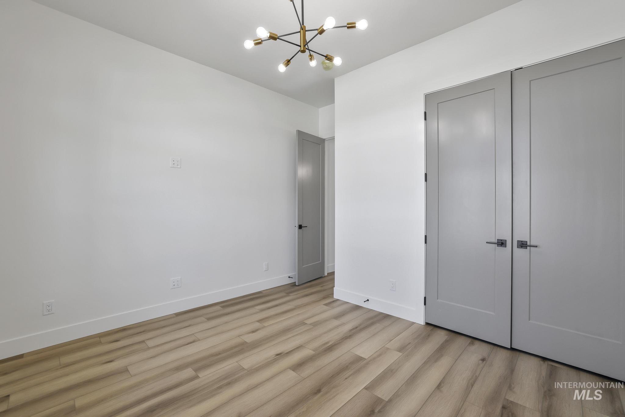 521 Falling Leaf Lane Twin Falls, ID 83301 - Photo 23 of 42 Unfurnished bedroom featuring a chandelier, light wood finished floors, and a closet
