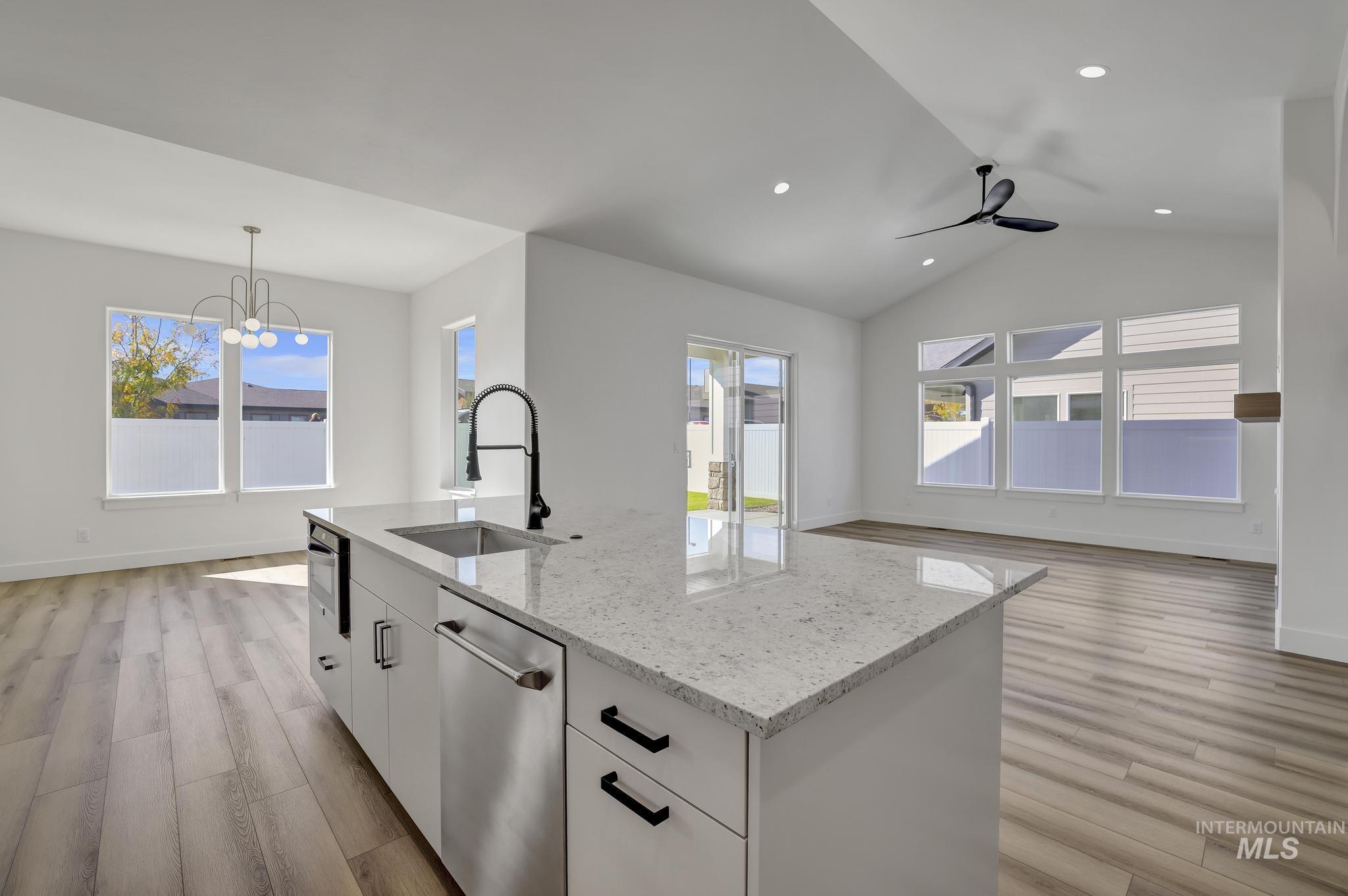 521 Falling Leaf Lane Twin Falls, ID 83301 - Photo 42 of 42 Kitchen featuring white cabinetry, light stone countertops, open floor plan, healthy amount of natural light, and lofted ceiling