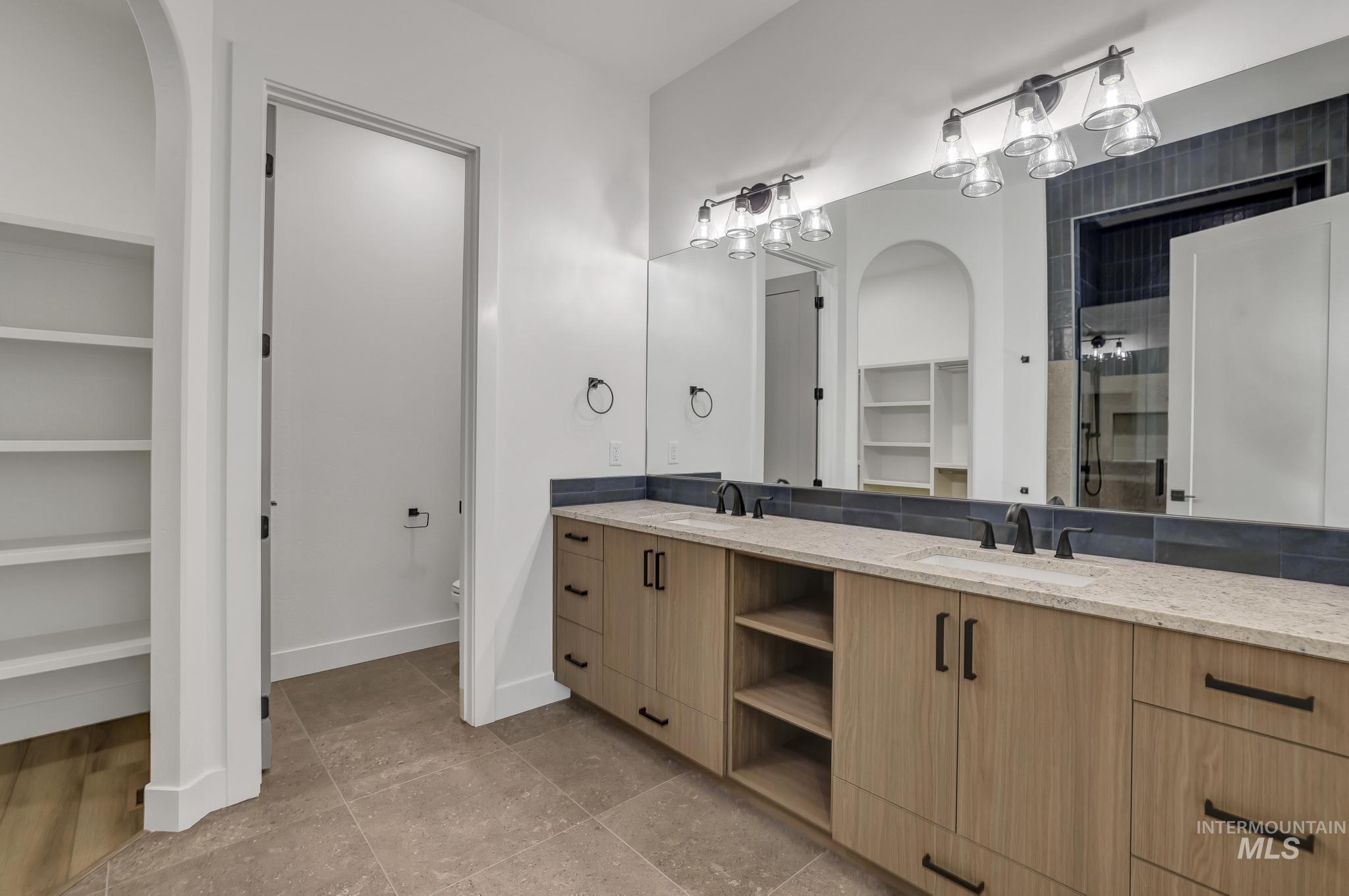 521 Falling Leaf Lane Twin Falls, ID 83301 - Photo 31 of 42 Bathroom featuring a walk in closet, double vanity, a stall shower, light tile patterned flooring, and built in shelves