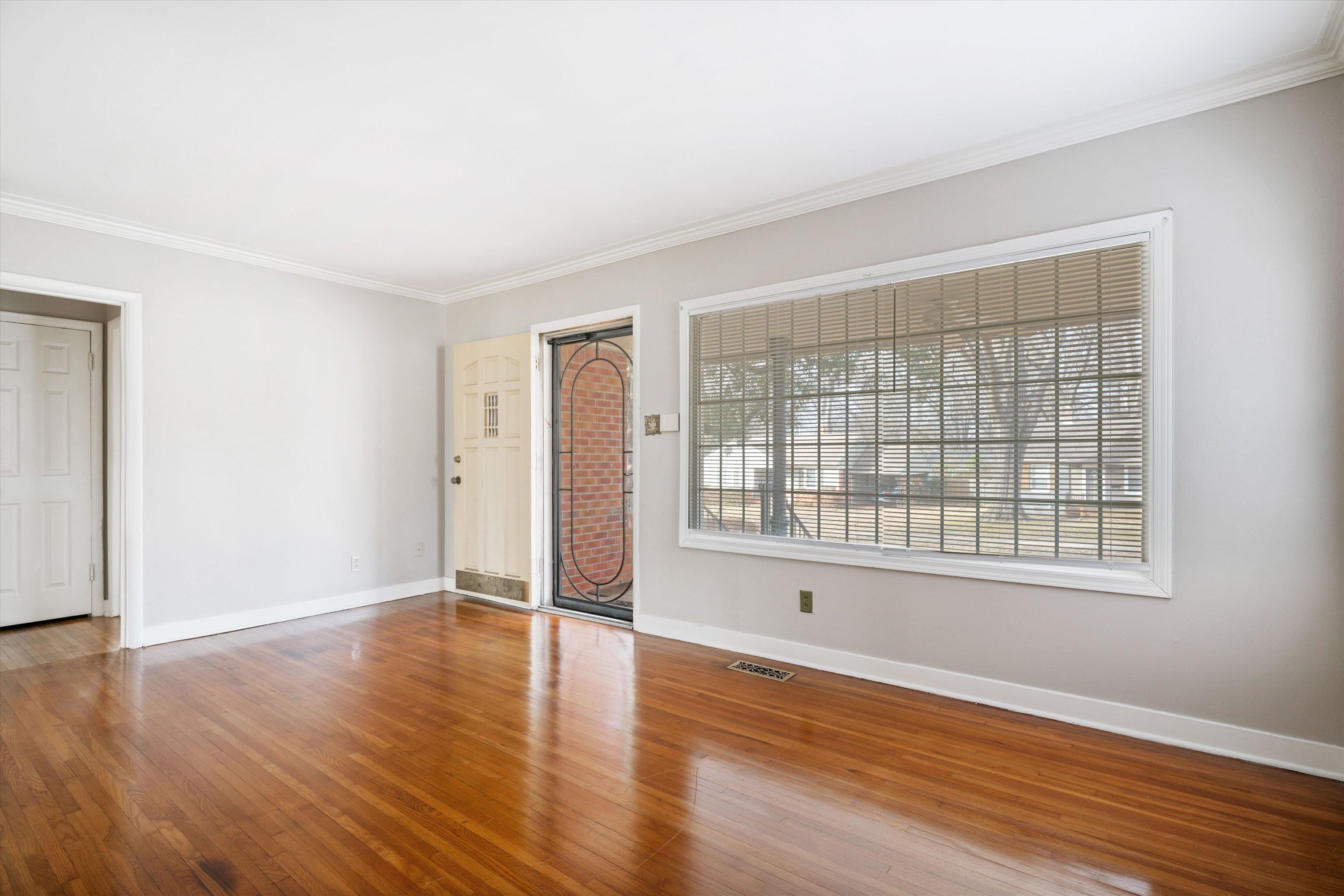 4863 Amboy Road Memphis, TN 38117 - Photo 6 of 26 a view of an empty room with wooden floor and a window