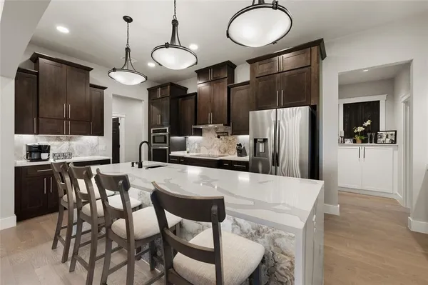 a kitchen with stainless steel appliances kitchen island granite countertop a refrigerator a stove a microwave oven a sink with island and chairs