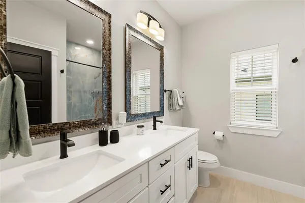 a bathroom with double vanity sink a mirror and a toilet