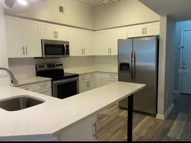 a kitchen with stainless steel appliances a refrigerator sink and microwave