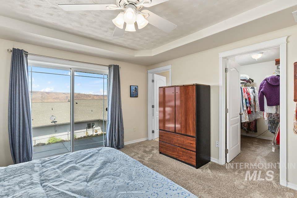 2924 27th Street Clarkston, WA 99403 - Photo 23 of 36 Bedroom with light carpet, access to outside, a walk in closet, ceiling fan, and a tray ceiling