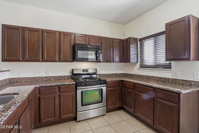 a kitchen with stainless steel appliances granite countertop wooden cabinets sink stove and microwave