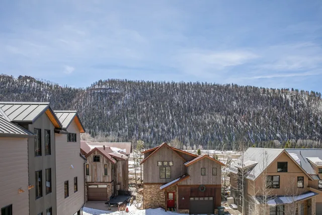 a front view of a house with a yard and mountain view in back
