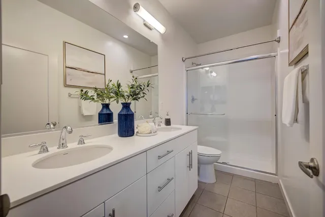 a bathroom with a double vanity sink toilet and shower