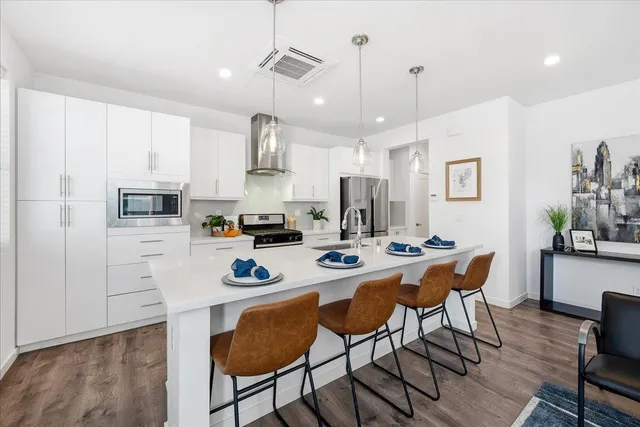 a kitchen with stainless steel appliances kitchen island granite countertop a sink a stove a dining table and chairs