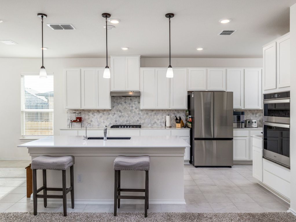 3921 Riardo Drive Round Rock, TX 78665 - Photo 7 of 27 a kitchen with stainless steel appliances granite countertop a refrigerator a sink a stove a microwave a center island and cabinets