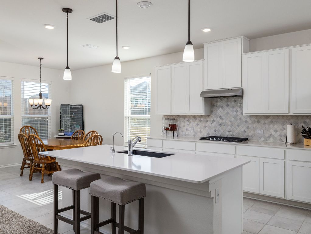3921 Riardo Drive Round Rock, TX 78665 - Photo 8 of 27 a kitchen with stainless steel appliances granite countertop a sink a center island a stove and a wooden floor