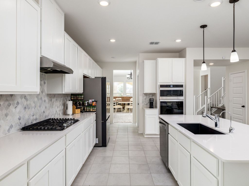 3921 Riardo Drive Round Rock, TX 78665 - Photo 10 of 27 a kitchen with stainless steel appliances kitchen island a sink a stove and a refrigerator