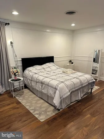 a bedroom with a bed a mirror and wooden floor