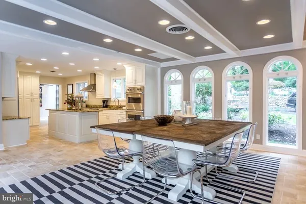 a dining hall with stainless steel appliances granite countertop a stove a sink a refrigerator and chairs