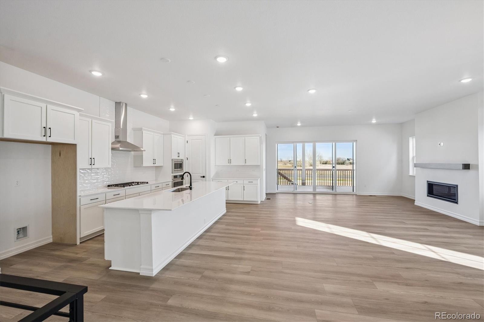 1180 Weller Street Timnath, CO 80547 - Photo 5 of 26 a large kitchen with stainless steel appliances kitchen island a large counter top and a stove top oven