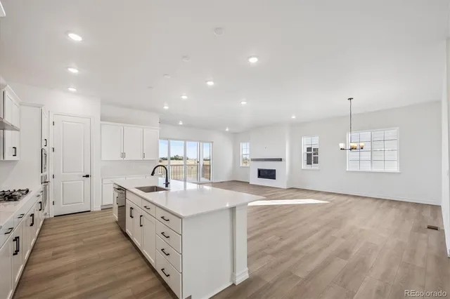a kitchen with stainless steel appliances granite countertop a sink stove and white cabinets with wooden floor