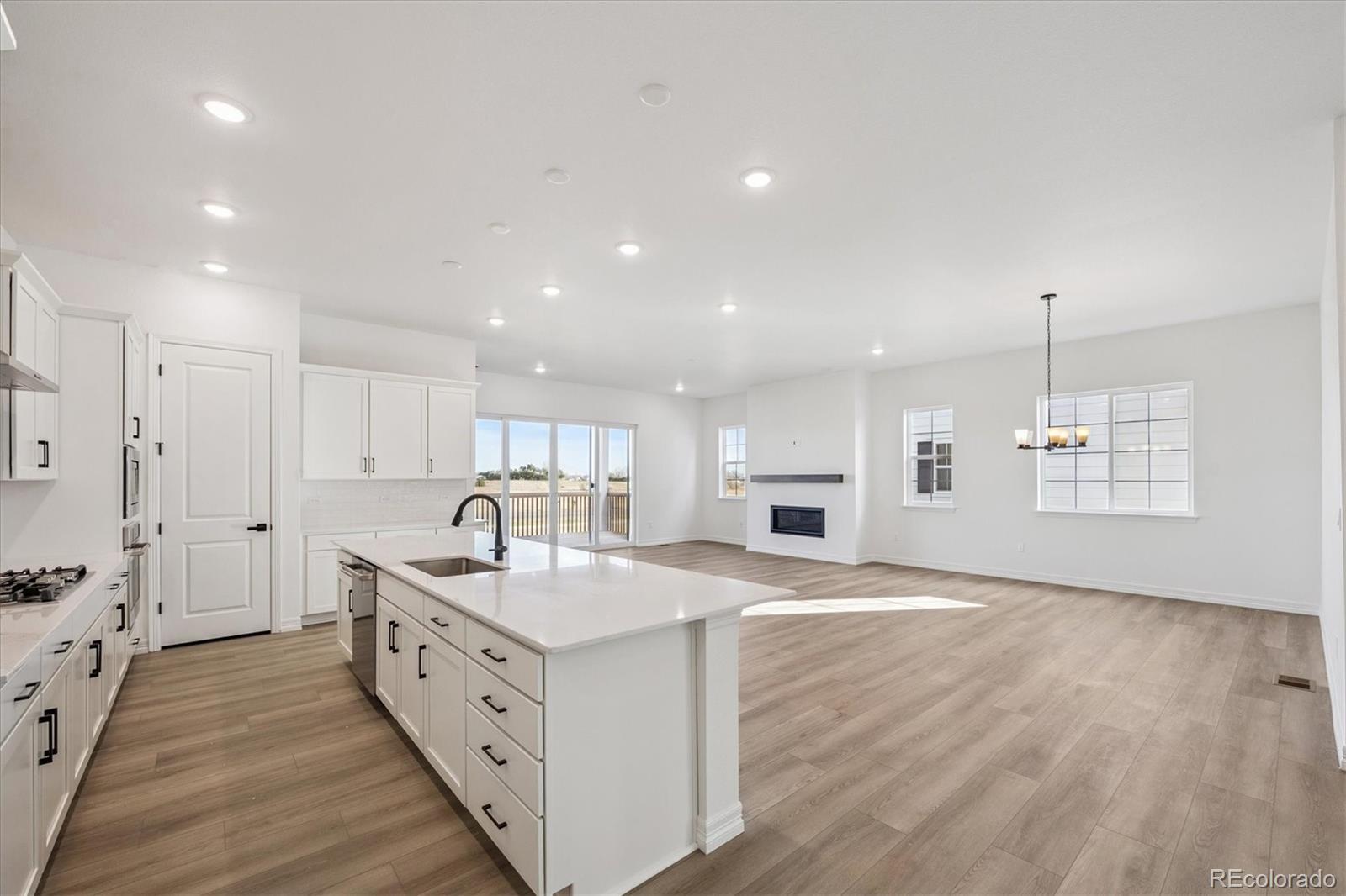 1180 Weller Street Timnath, CO 80547 - Photo 6 of 26 a kitchen with stainless steel appliances granite countertop a sink stove and white cabinets with wooden floor