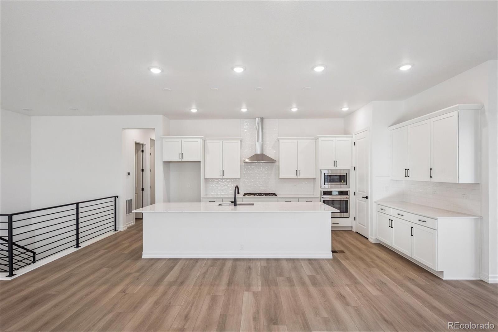 1180 Weller Street Timnath, CO 80547 - Photo 9 of 26 a view of a kitchen with center island stainless steel appliances wooden floor and windows
