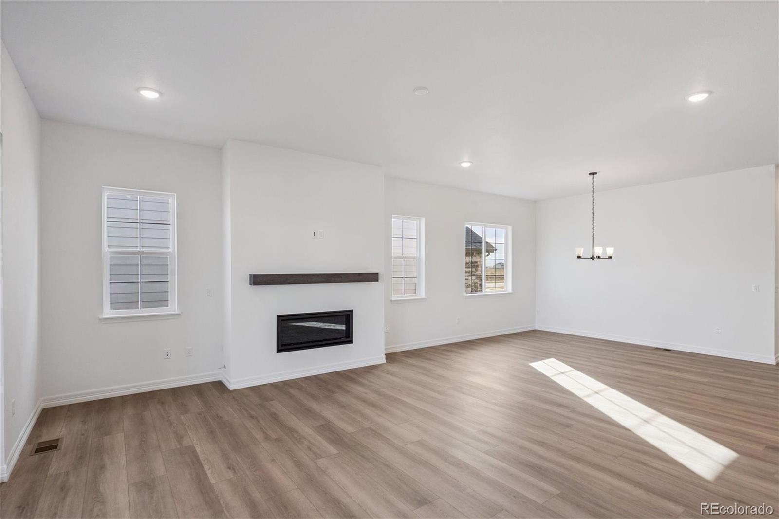 1180 Weller Street Timnath, CO 80547 - Photo 10 of 26 an empty room with wooden floor fireplace and windows