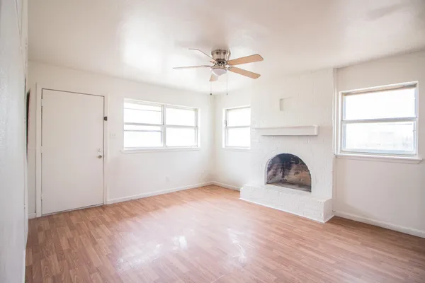 an empty room with windows and fireplace