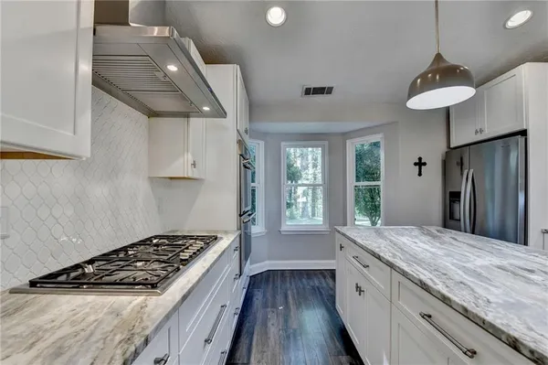 a large kitchen with kitchen island a stove a sink a counter space and cabinets