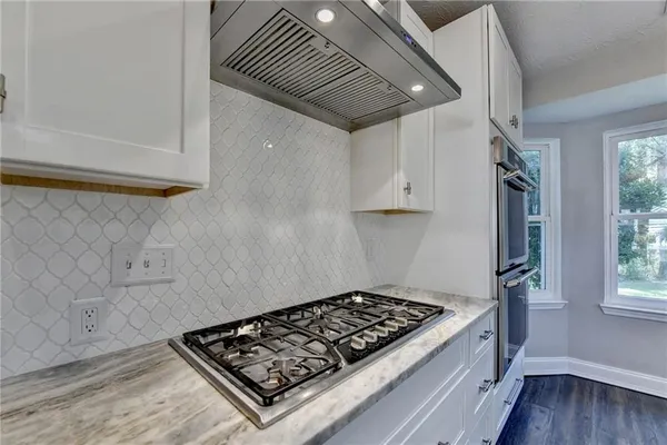 a kitchen with kitchen island granite countertop a sink appliances cabinets and a large window