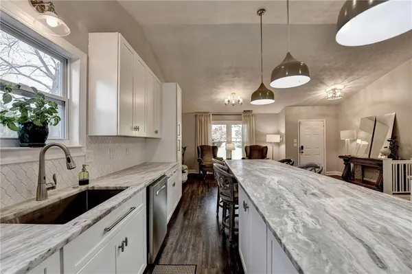 a kitchen with granite countertop a sink a counter top space stainless steel appliances and cabinets