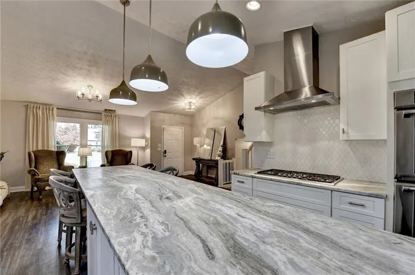 a kitchen with stainless steel appliances granite countertop a stove a sink dishwasher and a large refrigerator with wooden floor