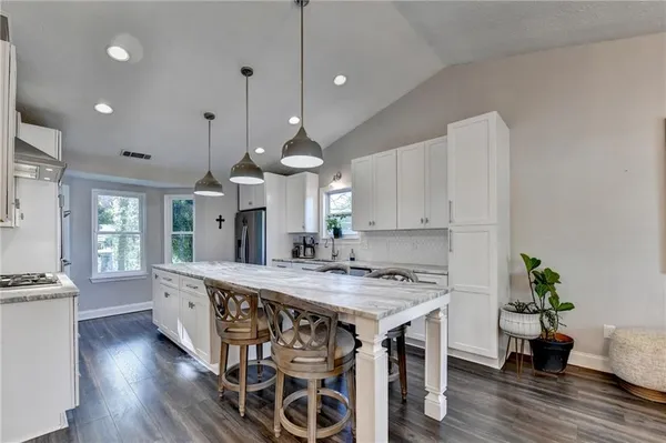a kitchen with stainless steel appliances granite countertop a sink a stove and a wooden floors