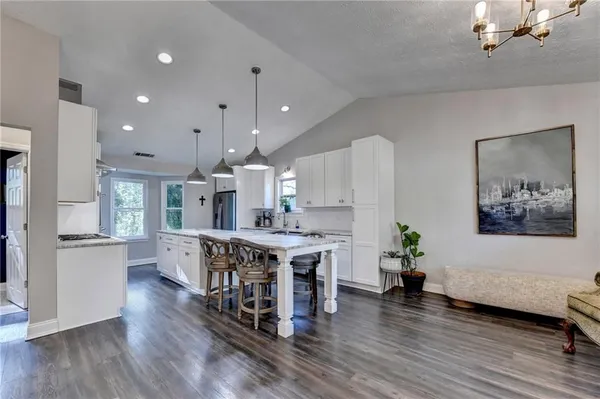 a kitchen with granite countertop a stove a sink dishwasher a refrigerator and wooden cabinets