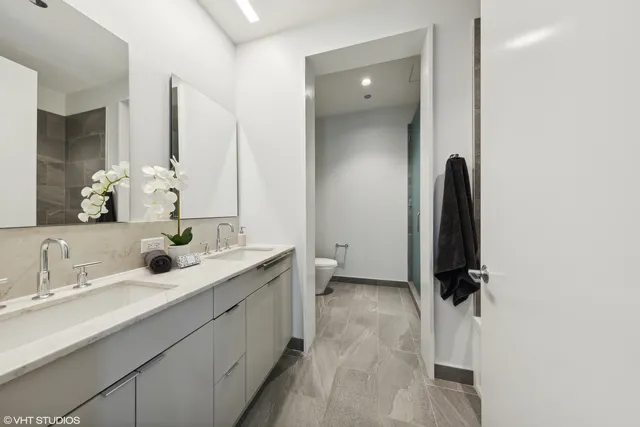 a bathroom with a double vanity sink a toilet and a mirror