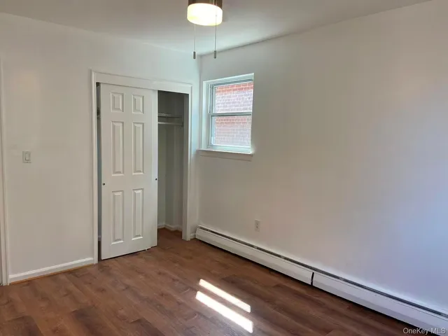 an empty room with wooden floor cabinet and windows