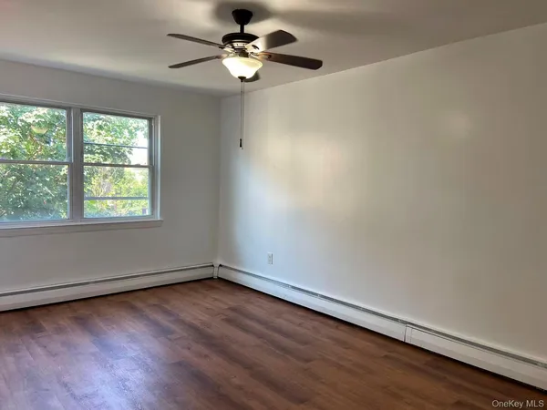 an empty room with wooden floor fan and windows
