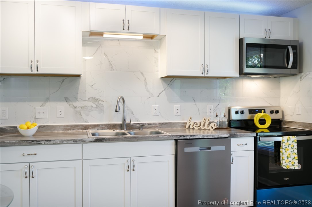 4514 Ruby Road Fayetteville, NC 28311 - Photo 6 of 21 a kitchen with stainless steel appliances granite countertop a sink a stove a microwave and cabinets