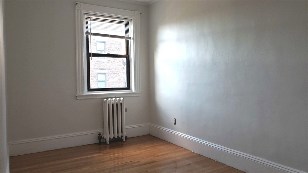 924 Beacon Street, Unit 6 Boston, MA 02215 - Photo 11 of 28 an empty room with wooden floor and a window