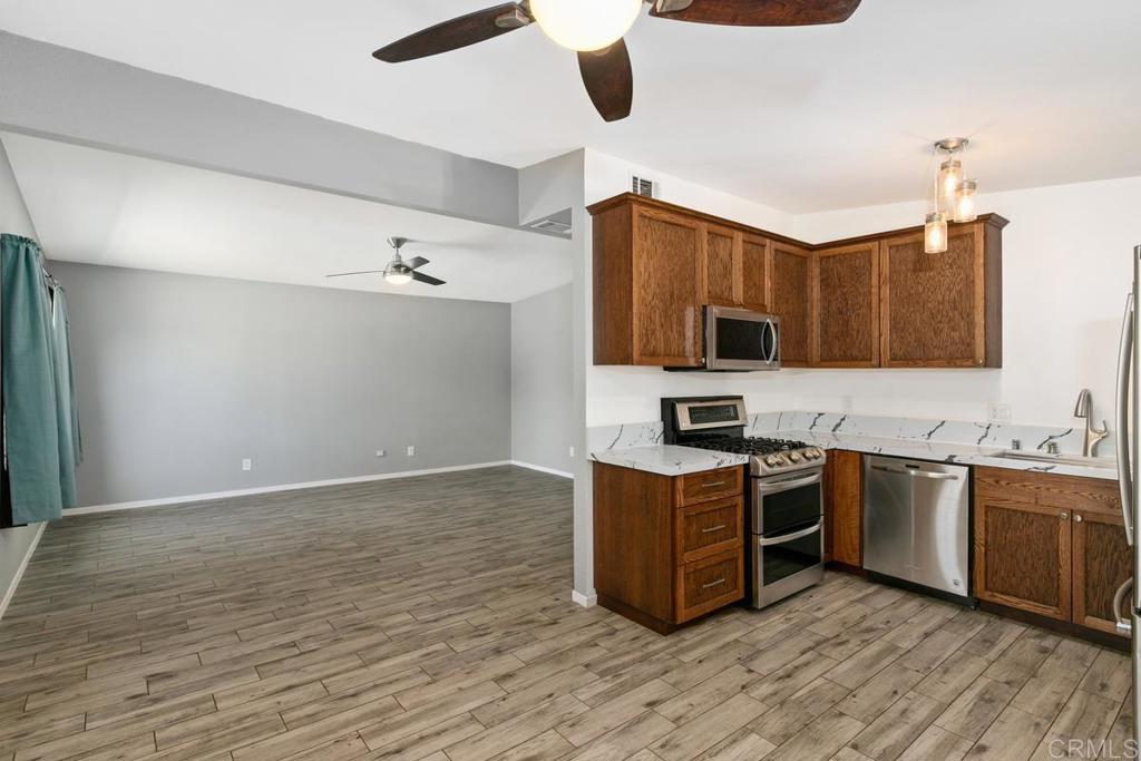 1451 Gowin Street Spring Valley, CA 91977 - Photo 7 of 24 a kitchen with stainless steel appliances granite countertop a stove top oven a sink with wooden floors