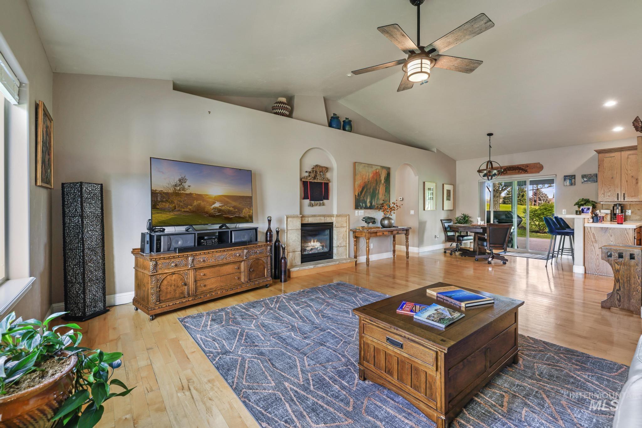 100 Olympic Road Jerome, ID 83338 - Photo 12 of 50 Spacious living area featuring wood-finish flooring, a fireplace with a stone surround, and vaulted ceilings