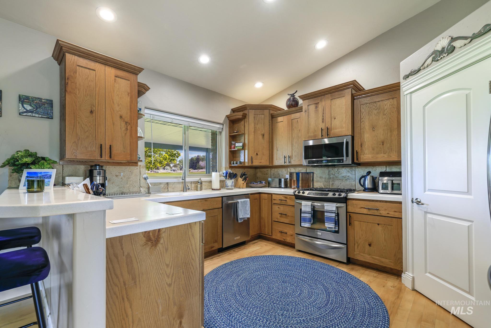 100 Olympic Road Jerome, ID 83338 - Photo 14 of 50 Kitchen featuring wood cabinetry, stainless steel appliances, white countertops, tile backsplash, and wood-finish flooring