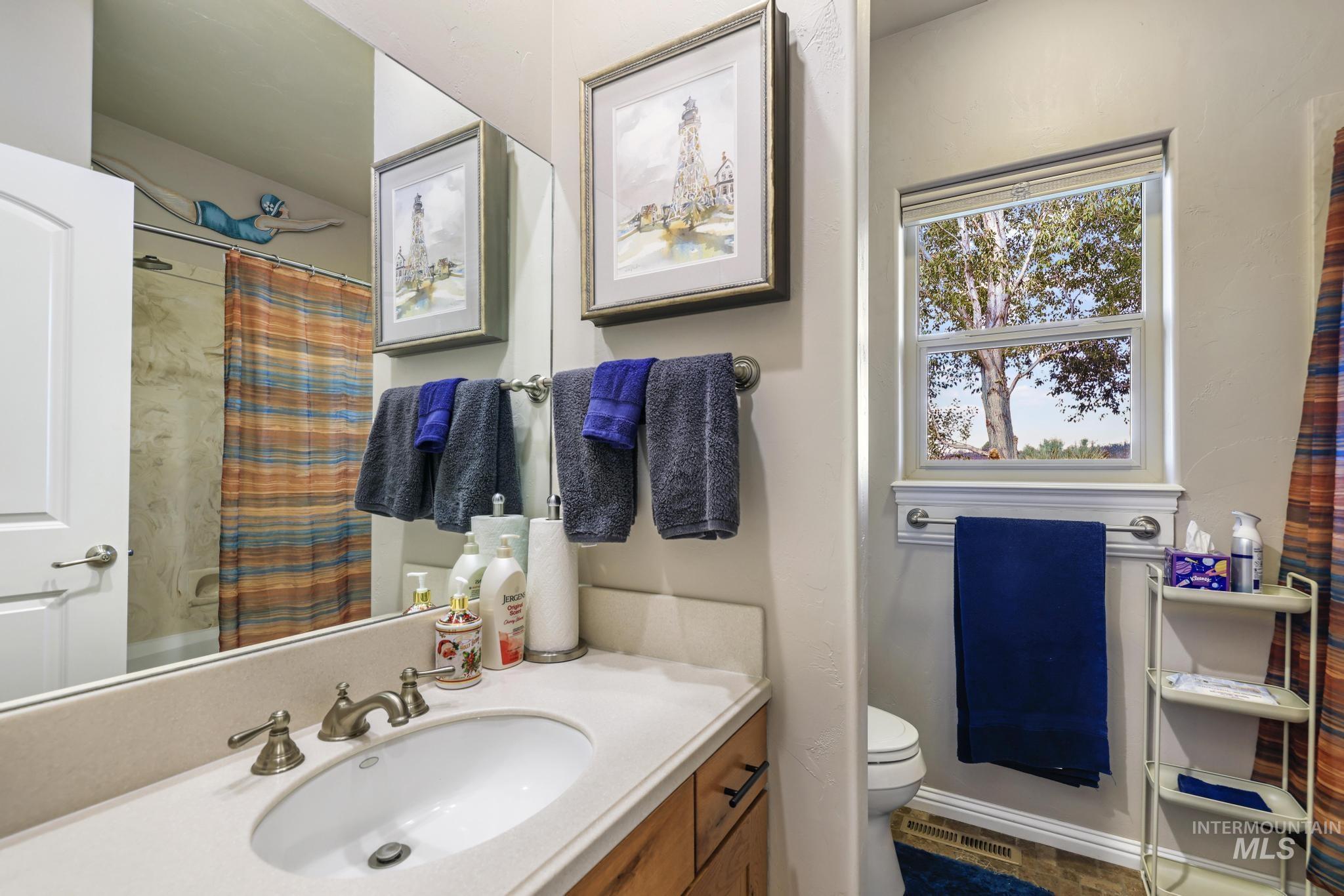 100 Olympic Road Jerome, ID 83338 - Photo 28 of 50 Bathroom featuring a single-sink vanity with a light-toned countertop, a large wall-mounted mirror, and a window with a tree backdrop