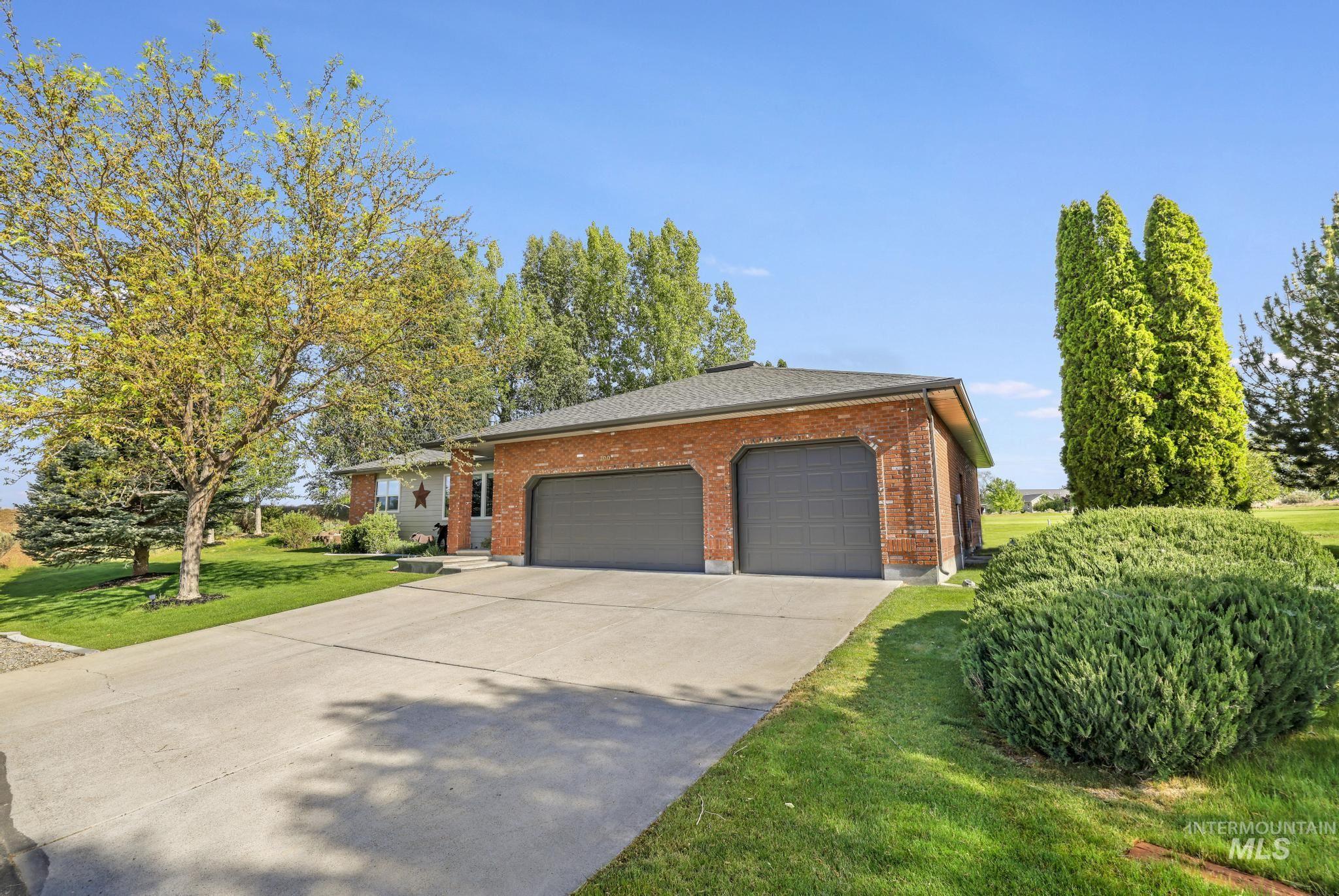 100 Olympic Road Jerome, ID 83338 - Photo 4 of 50 Brick-sided residence featuring a two-car garage with dark gray doors, a concrete driveway, and a shingled roof