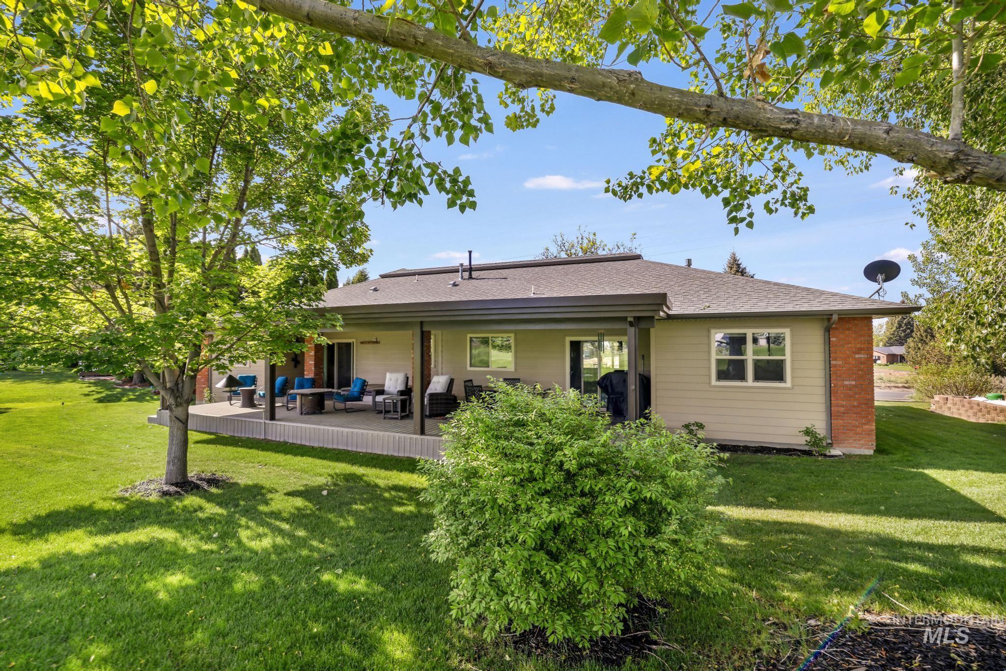 100 Olympic Road Jerome, ID 83338 - Photo 6 of 50 Expansive backyard featuring a manicured lawn, mature trees, and a covered back patio