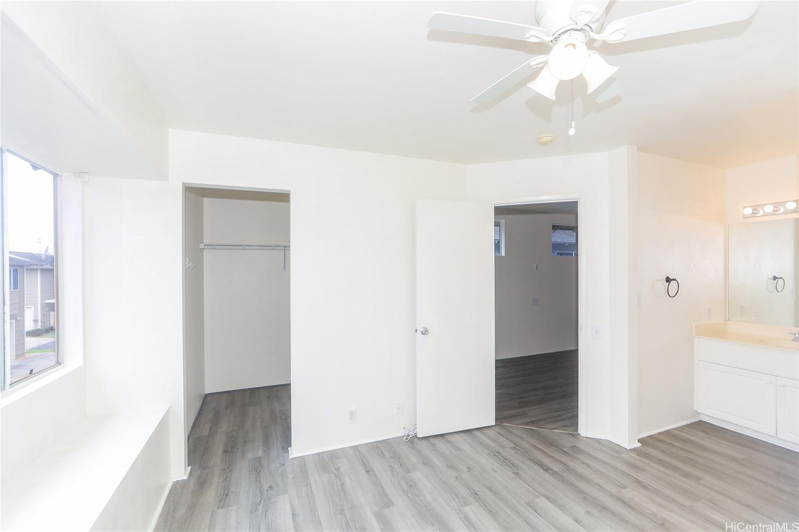 91-1011 Laulauna Street, Unit 136 Ewa Beach, HI 96706 - Photo 12 of 25 a view of a room with wooden floor and a ceiling fan