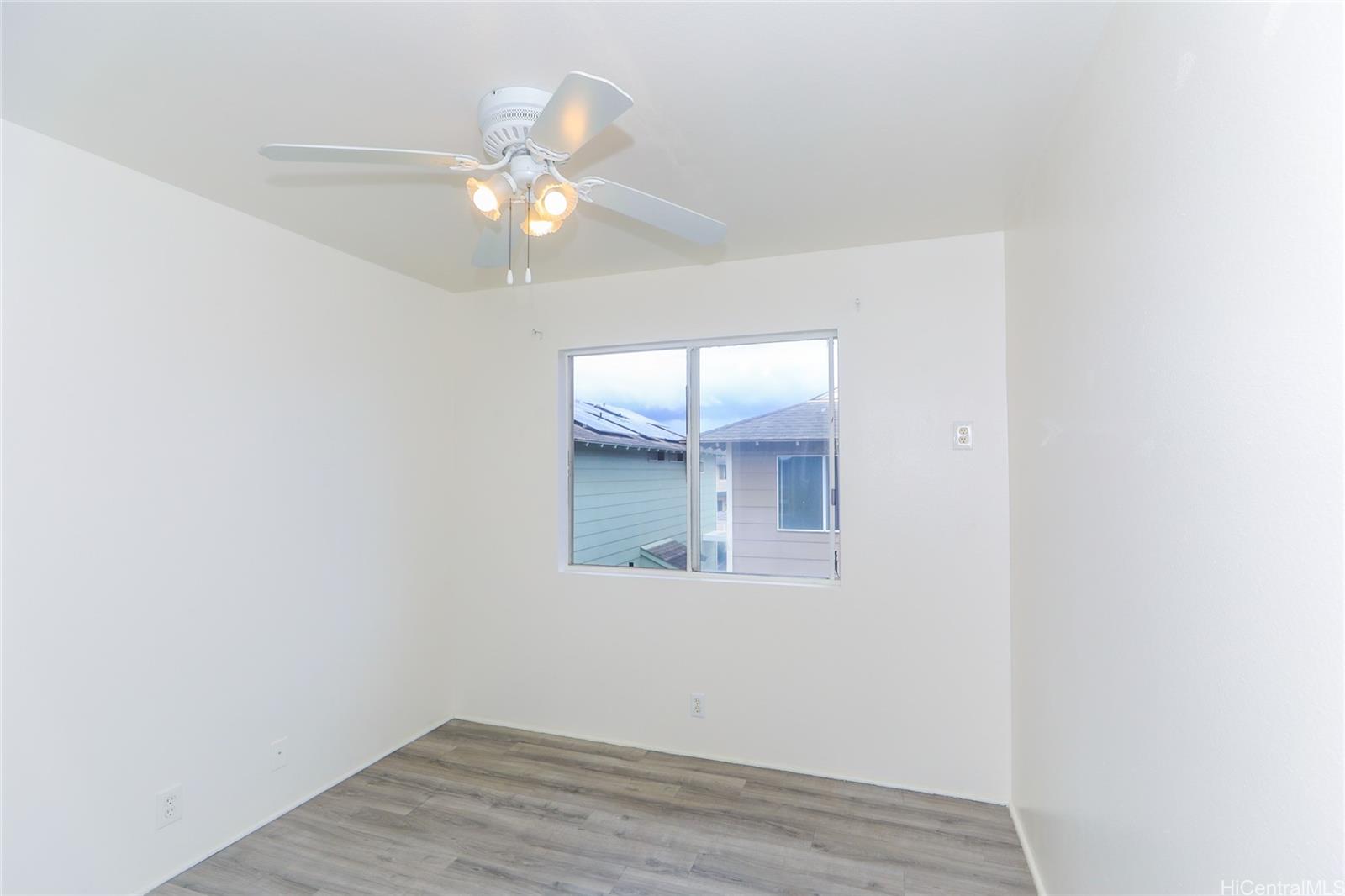 91-1011 Laulauna Street, Unit 136 Ewa Beach, HI 96706 - Photo 16 of 25 an empty room with wooden floor fan and window
