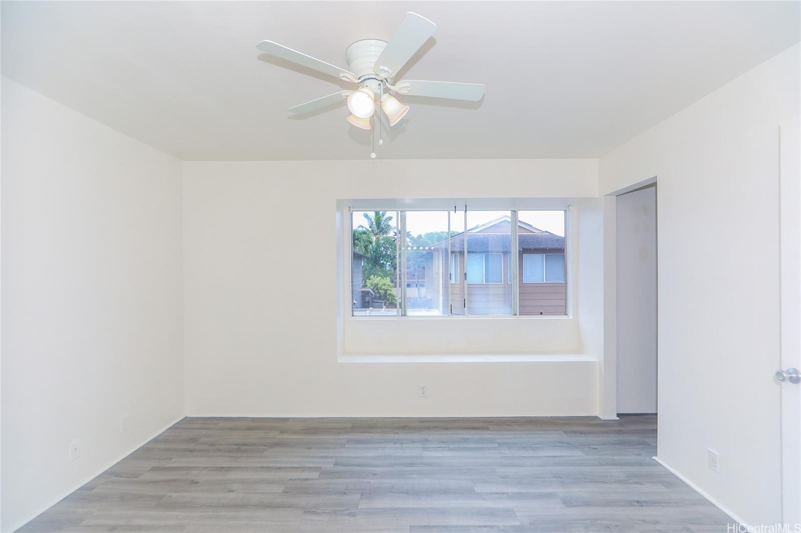 91-1011 Laulauna Street, Unit 136 Ewa Beach, HI 96706 - Photo 10 of 25 an empty room with wooden floor fan and windows