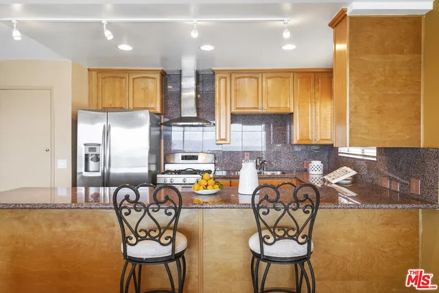 a kitchen with stainless steel appliances granite countertop a table chairs in it and wooden floors