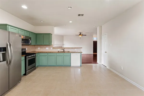 a kitchen with stainless steel appliances a sink a stove a refrigerator cabinets and a window
