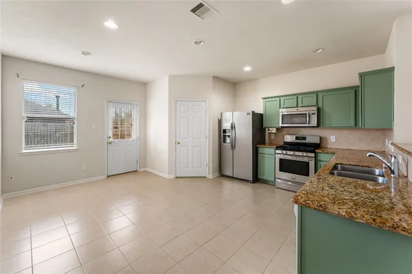 a kitchen with stainless steel appliances granite countertop a refrigerator a stove a sink and a microwave