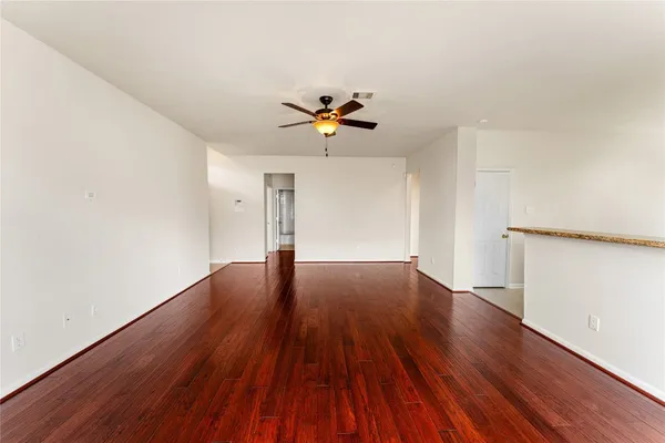 an empty room with wooden floor and a ceiling fan