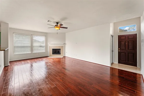 an empty room with wooden floor chandelier and windows