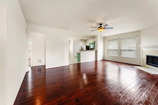 an empty room with wooden floor fireplace and windows